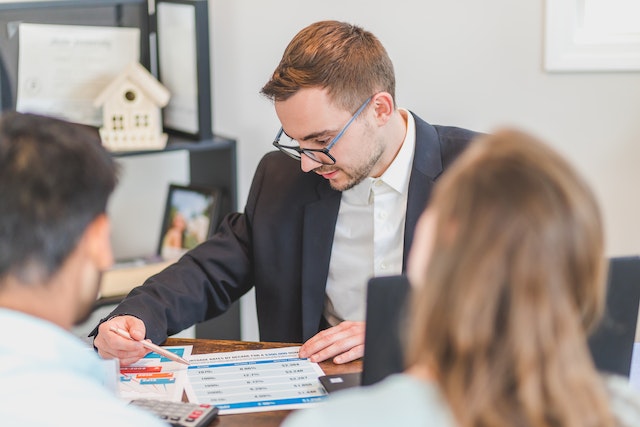 Property manager looking over a document, two people are sitting across the desk